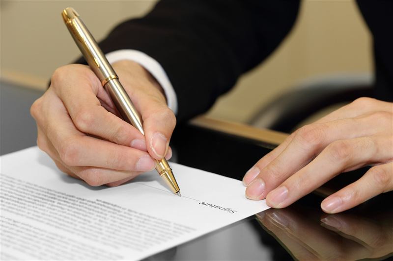 Mão assinando um contrato em papel