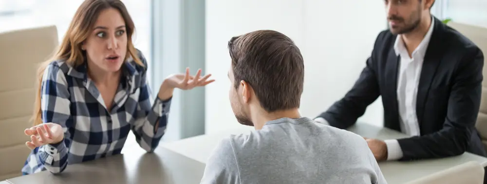 Casal discutindo diante de um advogado em uma sala de reunião